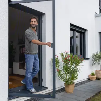 Mann �ffnet eine ma�gefertigte Fliegengitter T�r an einer modernen Terrasse