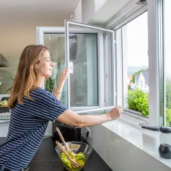 Frau �ffnet Fenster mit eingesetztem Drehfenster Spannrahmen in der K�che